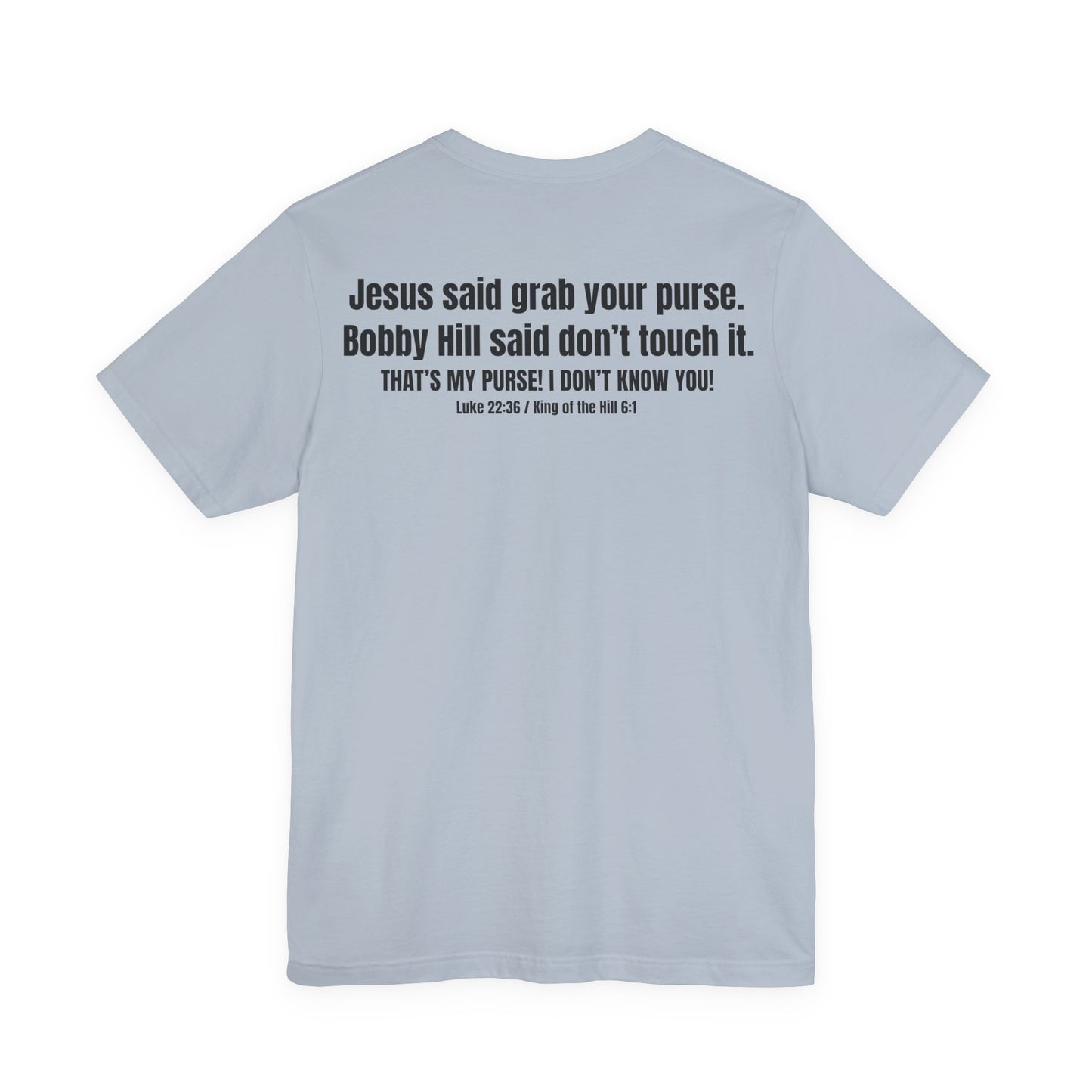 “Back of shirt with bold stacked text: ‘Jesus said grab your purse. Bobby Hill said don’t touch it.’ Below: ‘THAT’S MY PURSE! I DON’T KNOW YOU!’ and reference ‘Luke 22:36 / King of the Hill 6:1.