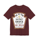 Front: Maroon unisex Christian t-shirt with a ketchup-label style graphic reading “He Is the Secret Sauce to Salvation — Be Bold in Jesus Name” with John 14:6 cross emblem.